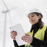 Femme souriante travaillant dans un parc olien en utilisant sa tablette